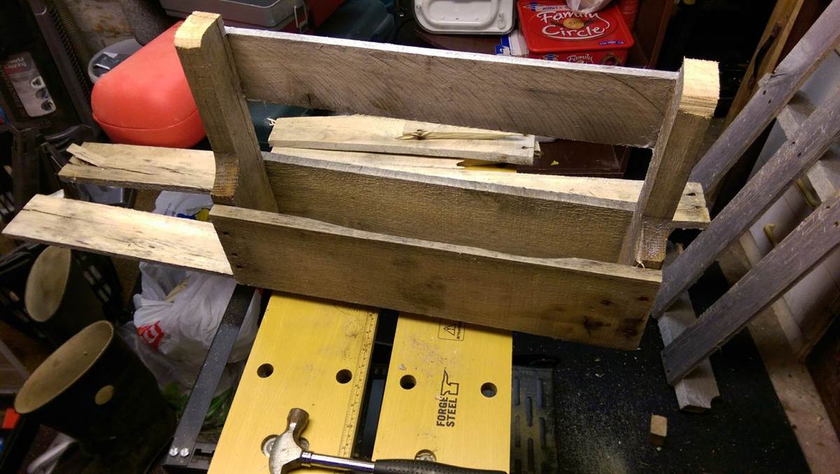 Frame being assembled from reclaimed pallet wood on a workbench before finishing